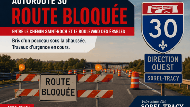 Large banner announcing Autoroute 30 route bloquée with roadblock barriers and traffic cones on a highway surface.